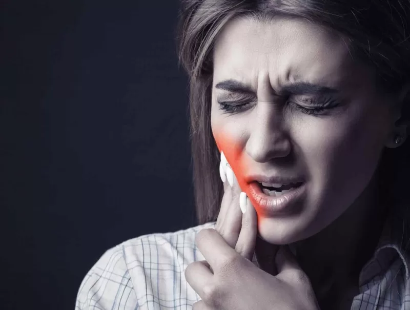 Woman holding both hands over mouth with tooth pain